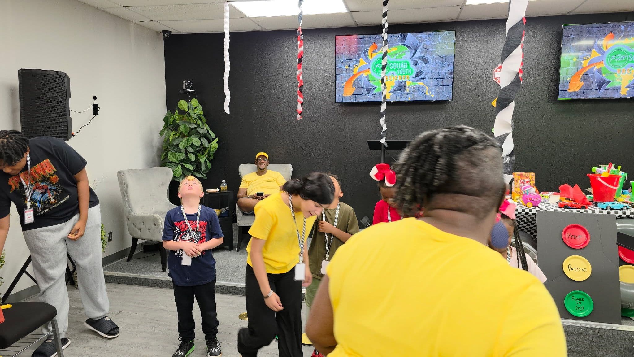 Volunteers in yellow shirts leading kids in an activity in the fellowship hall