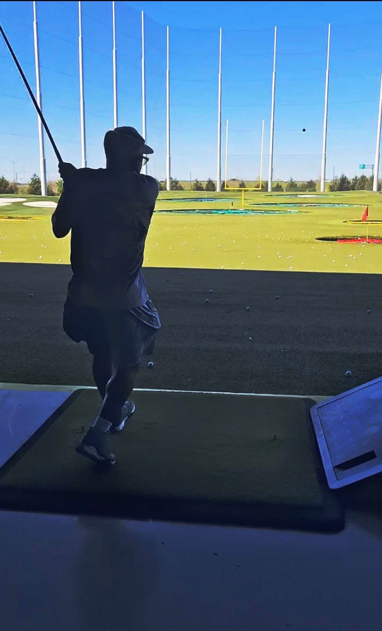 A men's ministry member swinging a golf club at a driving range outing