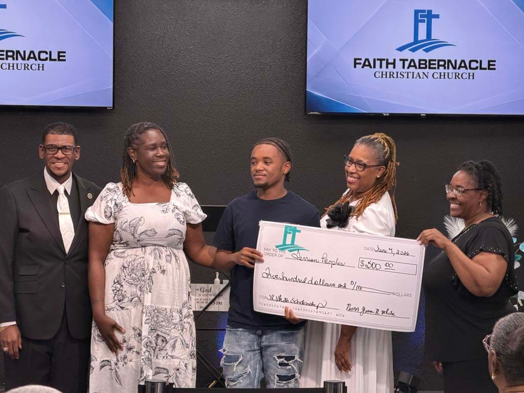 A young man accepting his FTCC scholarship check on stage alongside church leaders