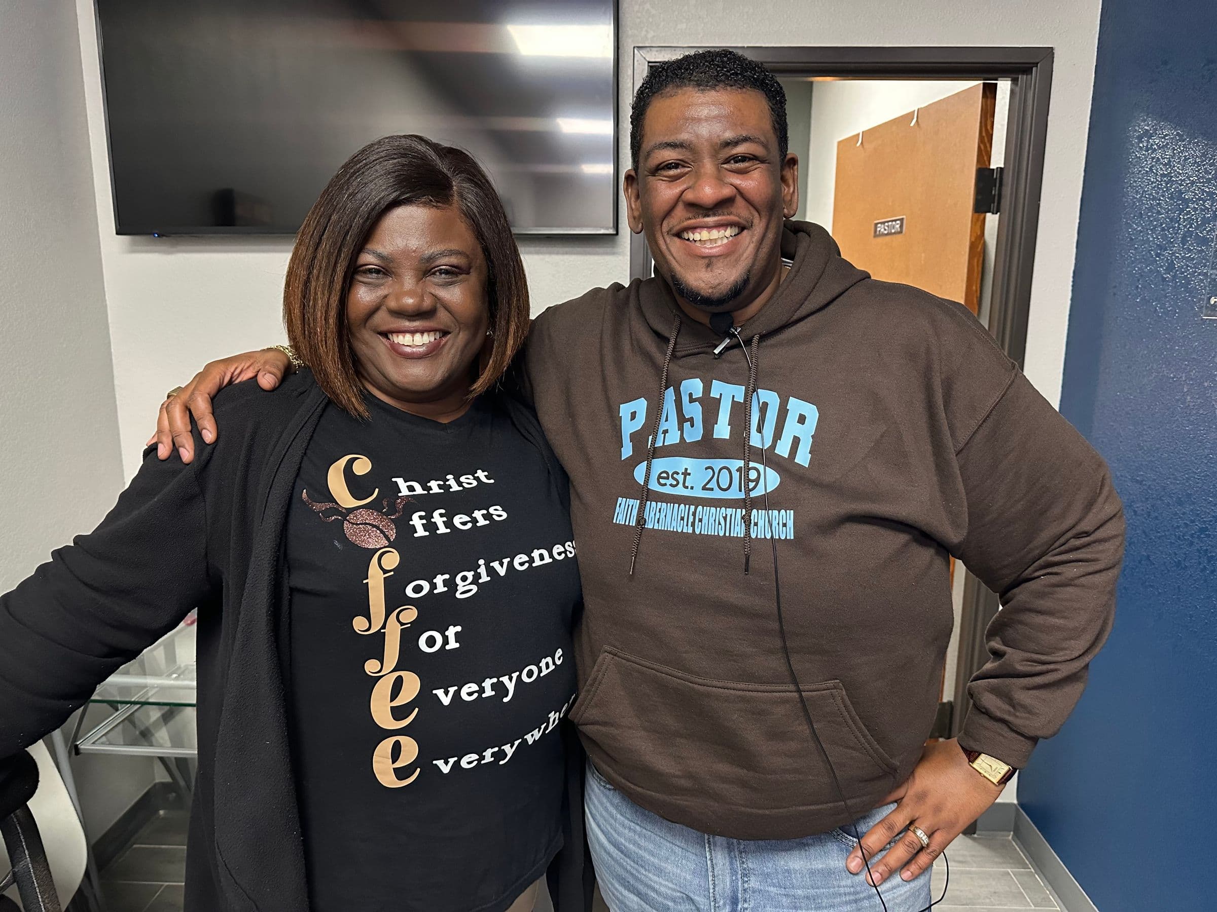 A pastor and a church member smiling arm in arm at Faith Tabernacle Christian Church
