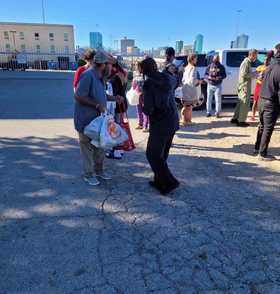 A volunteer handing bags of supplies to a man during an FTCC community outreach