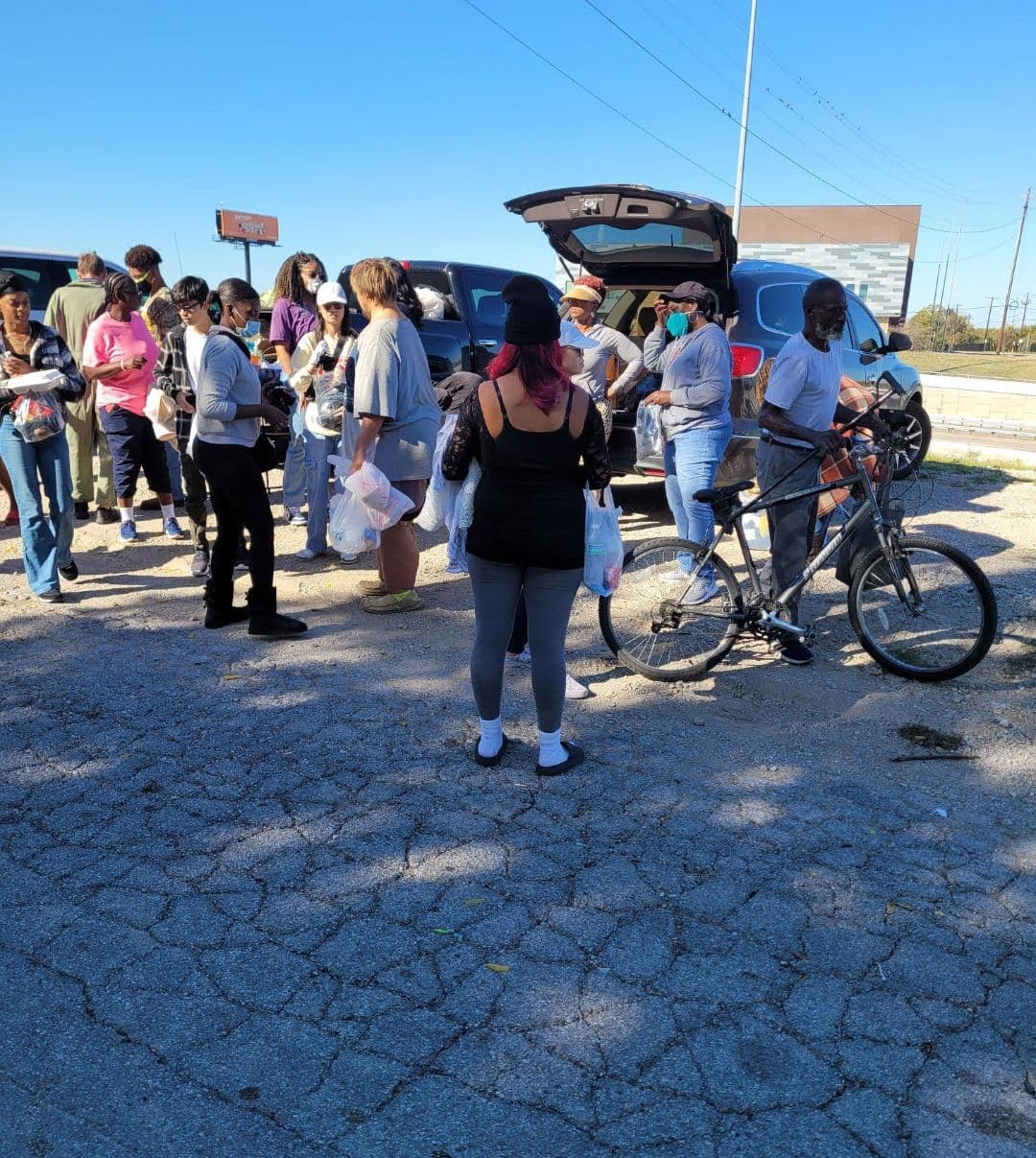 Outreach volunteers sharing bags of essentials from the back of an SUV