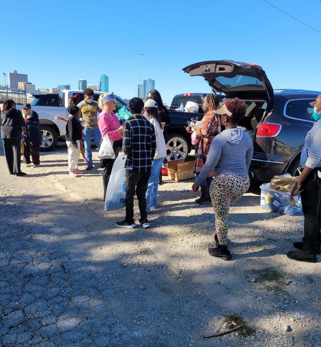FTCC volunteers handing out supplies from an open car trunk with the city skyline behind them