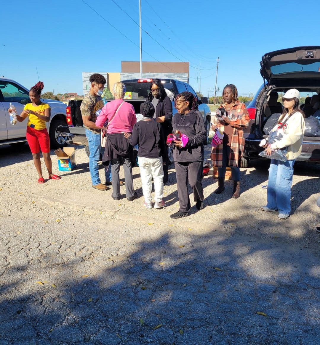 Outreach volunteers sharing drinks and supplies with people in a parking lot