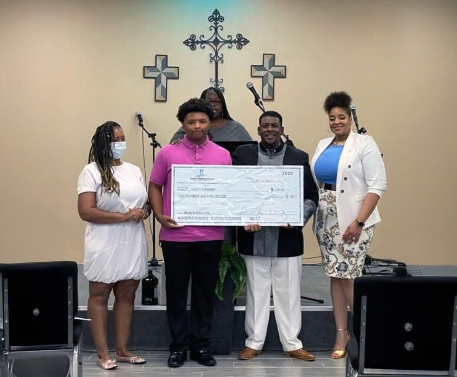 A student in a pink shirt holding a scholarship check beside FTCC leaders