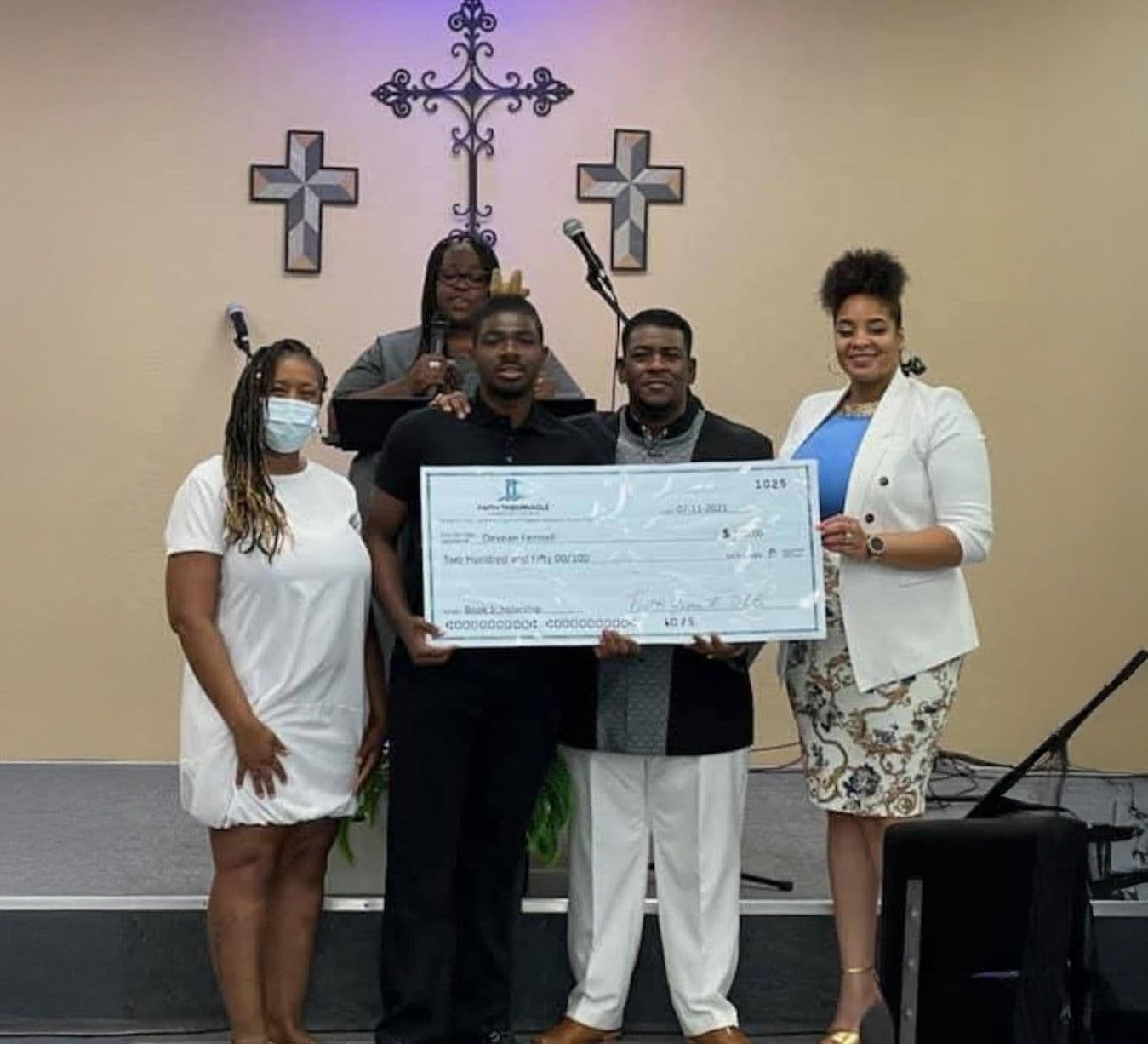 A scholarship recipient and FTCC leaders posing with an oversized check in the sanctuary
