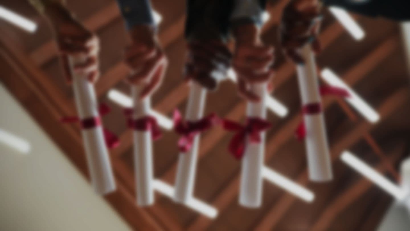 Graduates holding rolled diplomas tied with red ribbons
