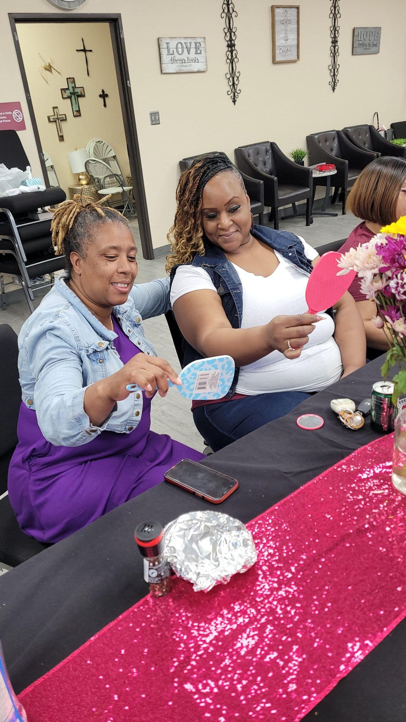 Women laughing together around a table with a pink sequin runner